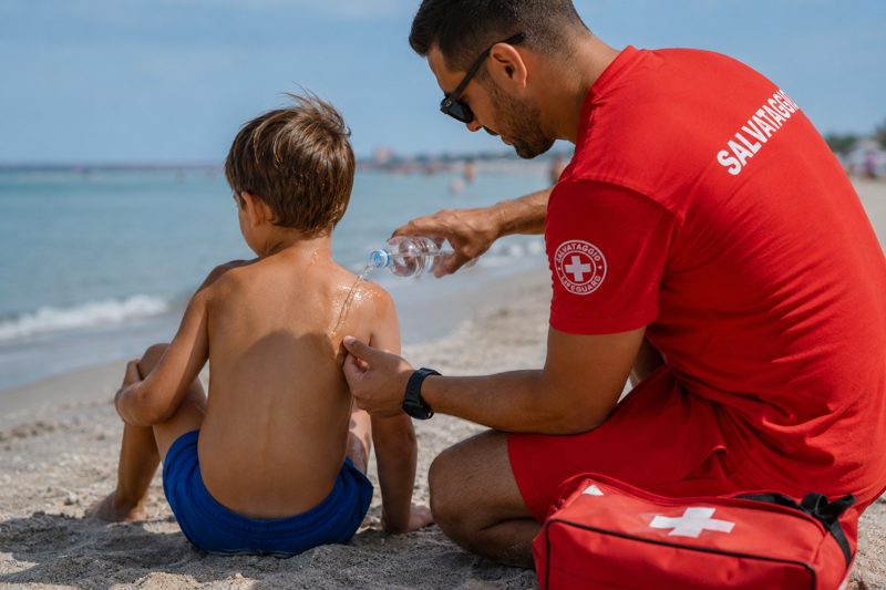 Risciacquo con acqua di mare dopo una puntura di medusa, primo intervento sulla spiaggia.
