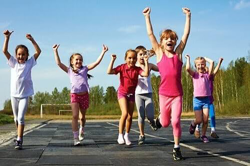 Bambine che corrono durante un'attività sportiva all'aperto, rappresentazione della pratica sportiva giovanile e del certificato medico non agonistico in Italia.