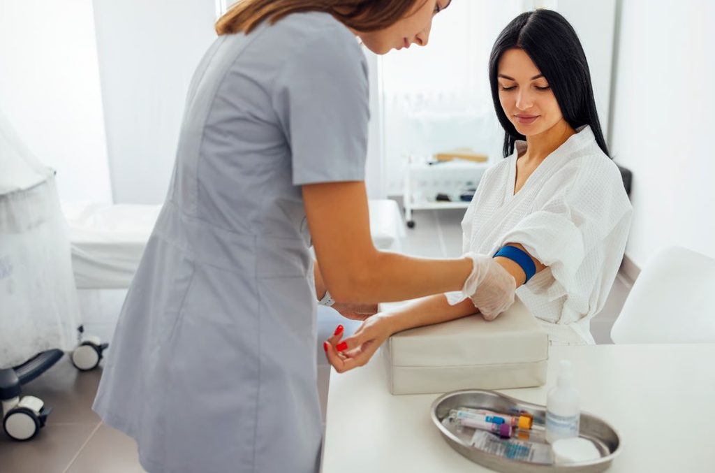 Operatore sanitario in un contesto clinico pulito mentre si prepara per un prelievo ematico destinato al dosaggio degli ormoni tiroidei.